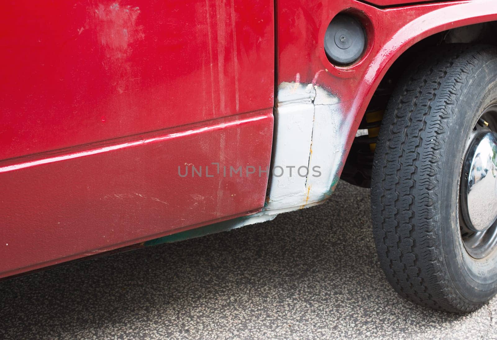Red old car was repaired, white color at the damage, old timer