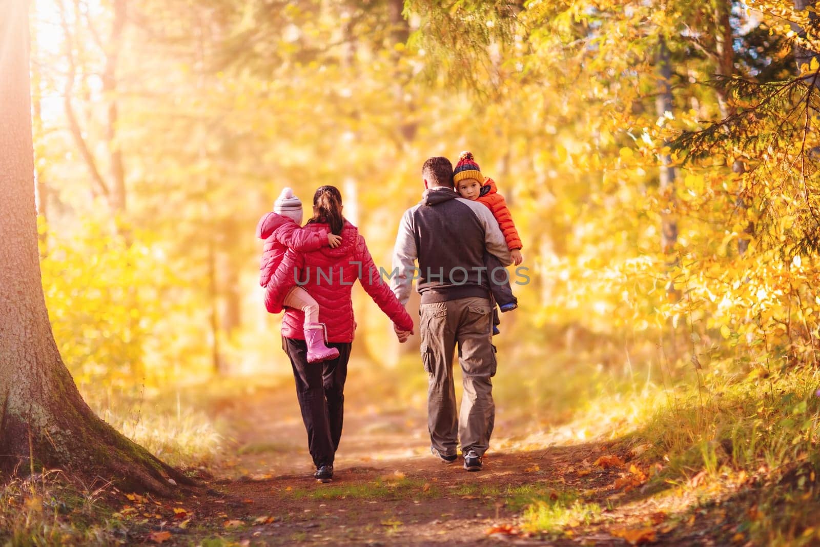 Family walking along the footpath in the autumnal natural park. Concept of family relationship and family weekends together.