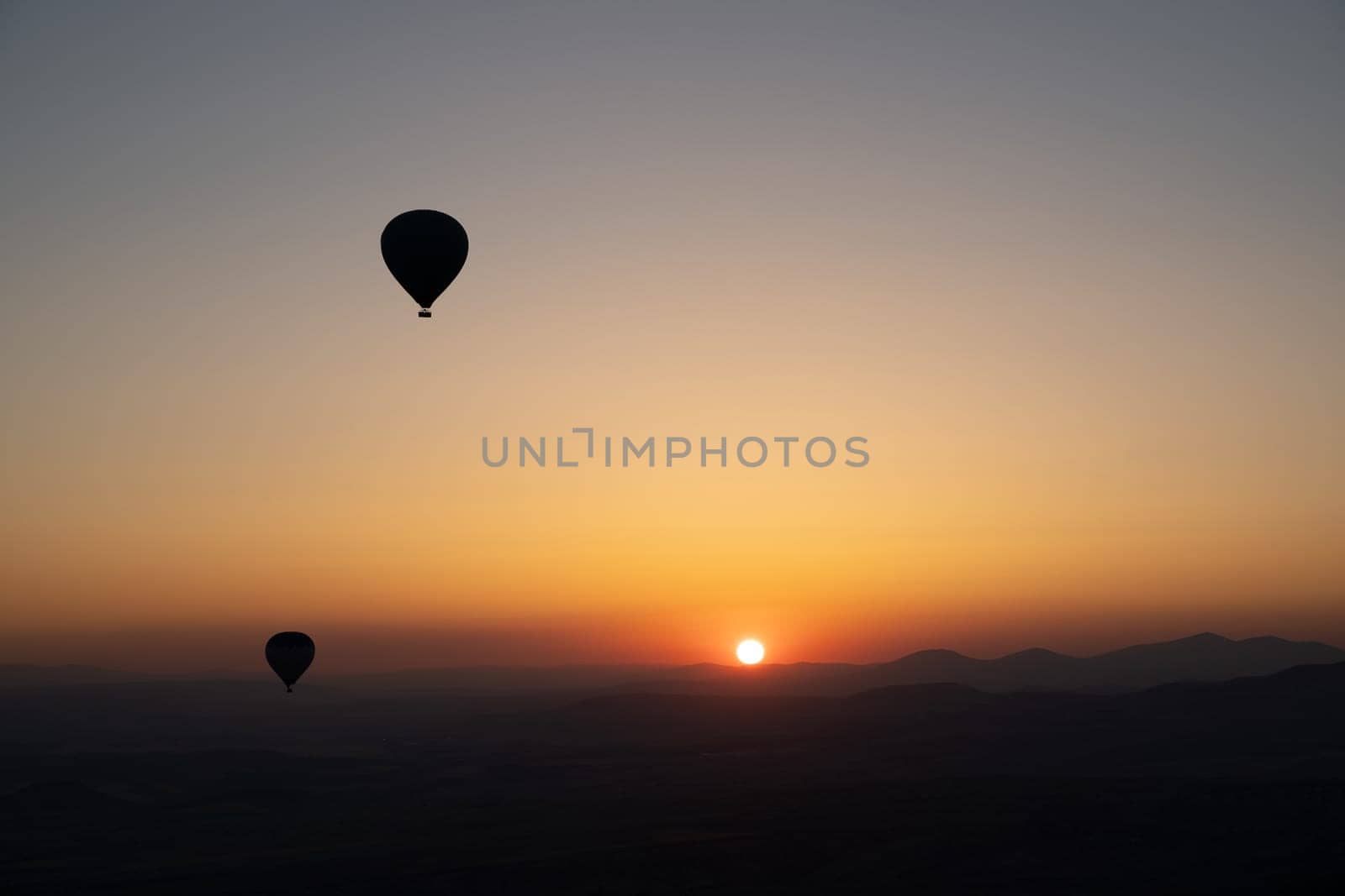 landscape with hot air balloons black silhouette rising up to the sky at sunrise with beautiful high mountain panorama in the background