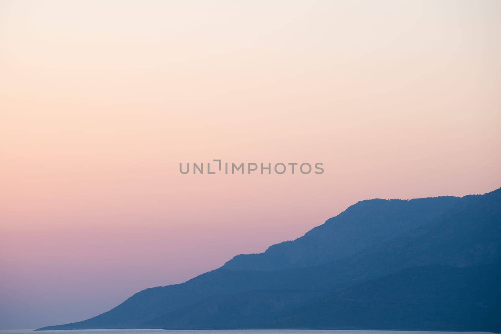 landscape of high mountains rising up on the ocean coast with beautiful gradient sunset sky in the background