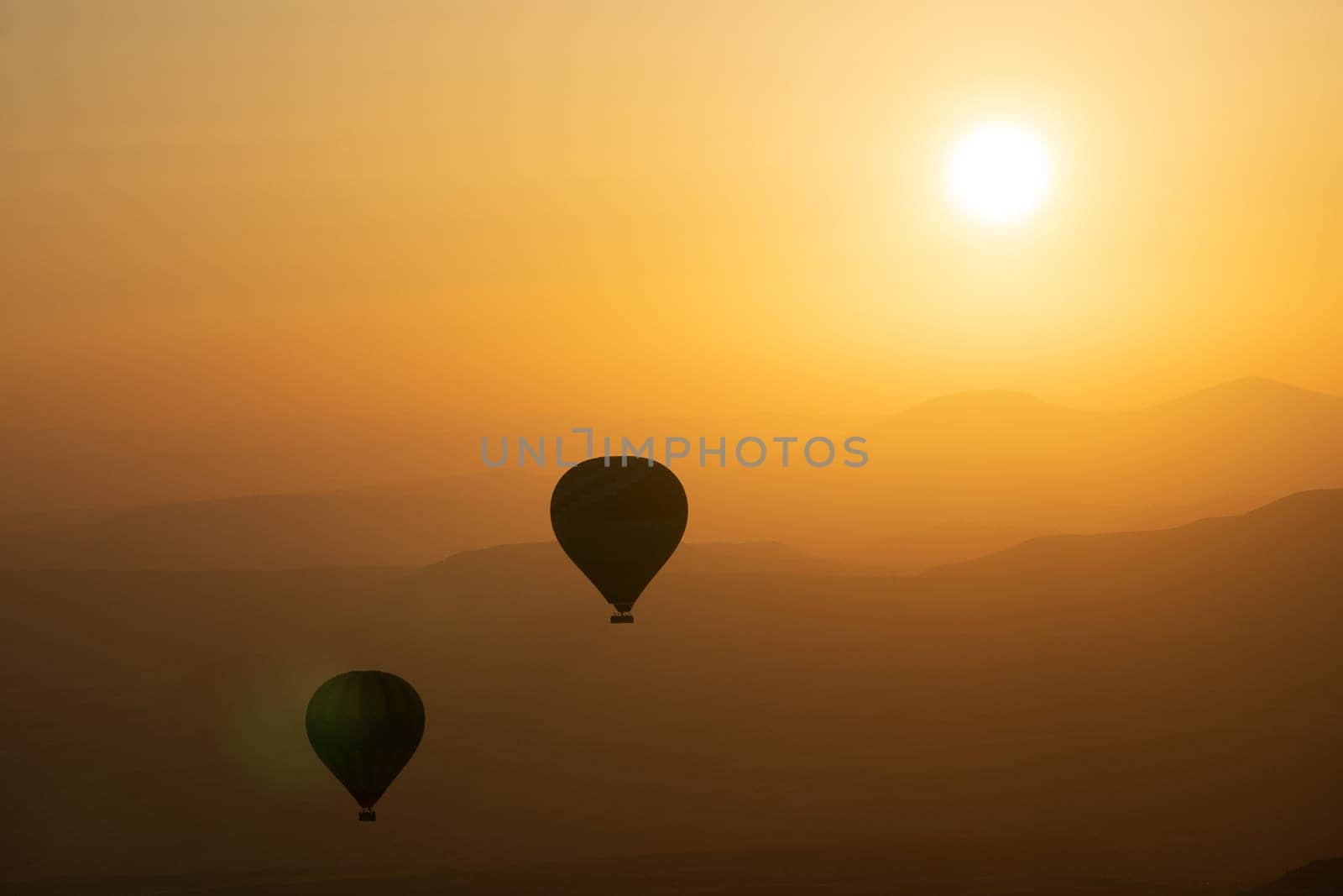 landscape with hot air balloons black silhouette rising up to the sky at sunrise with beautiful high mountain panorama in the background