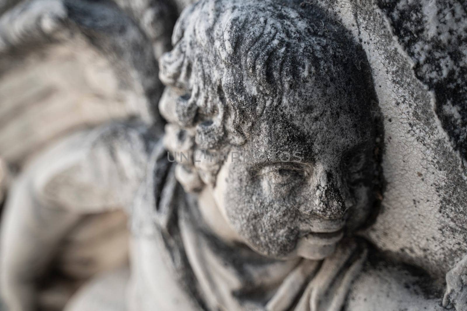 closeup perspective view of ancient stone basorelief of child head on old building postament