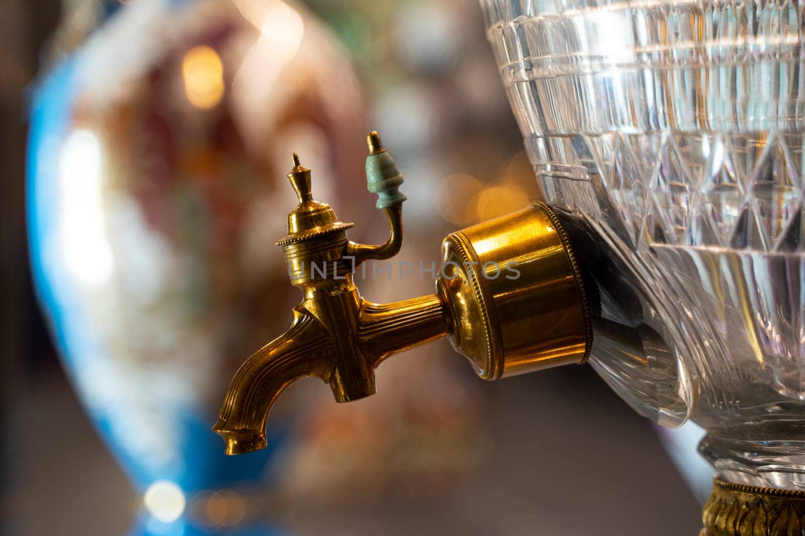 side view closeup of beautiful gold plated spigot with ceramic handle of luxurious glass samovar