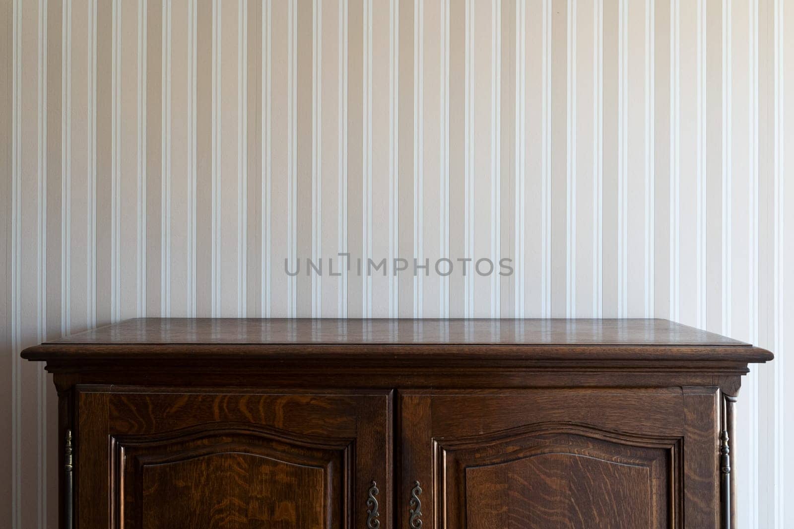 front view close up of empty brown vintage drawer wooden cabinet against a white wall with beige stripes