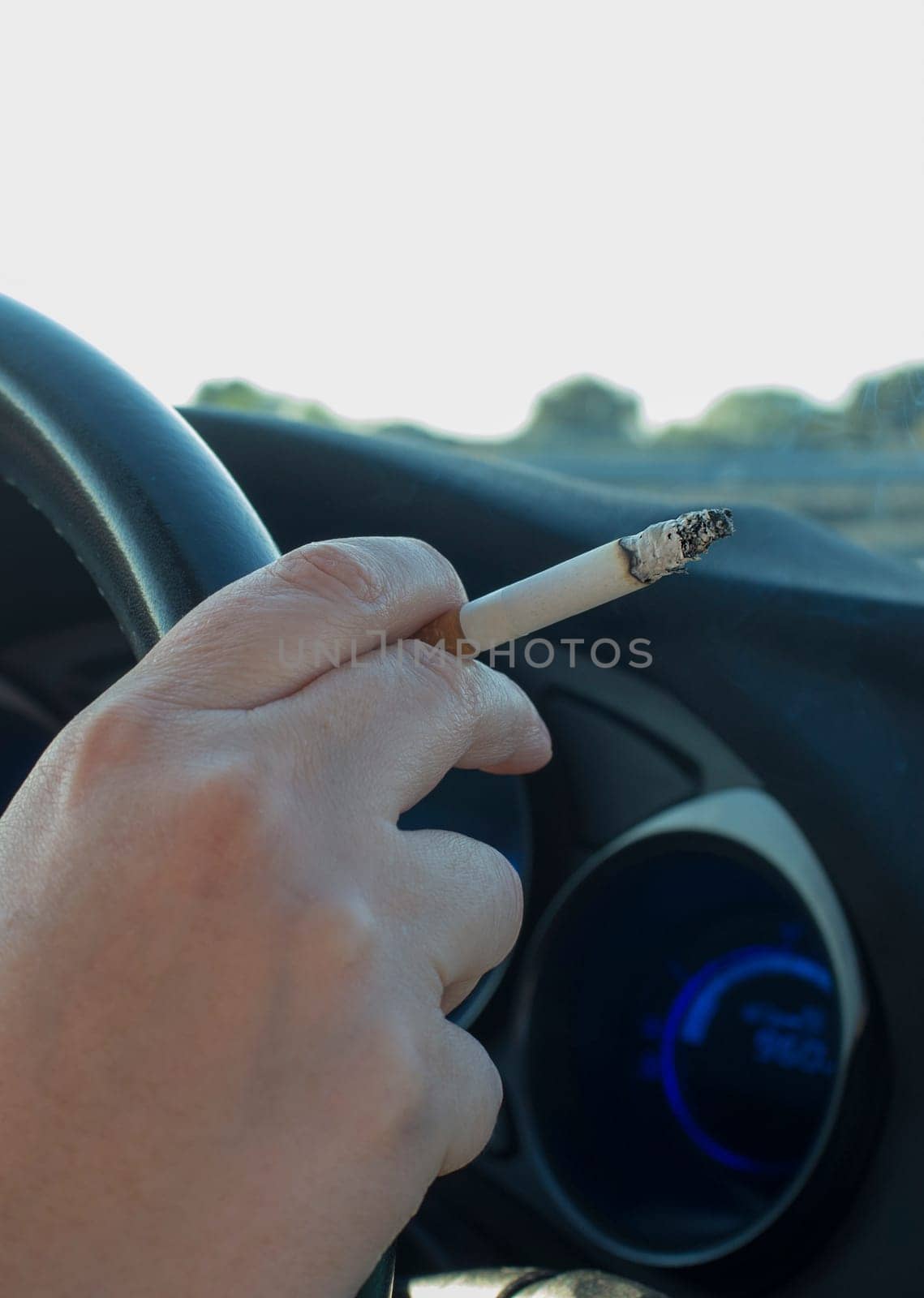 Woman smoking while she is driving. Cause of distracted driving accidents concept. Inside car view