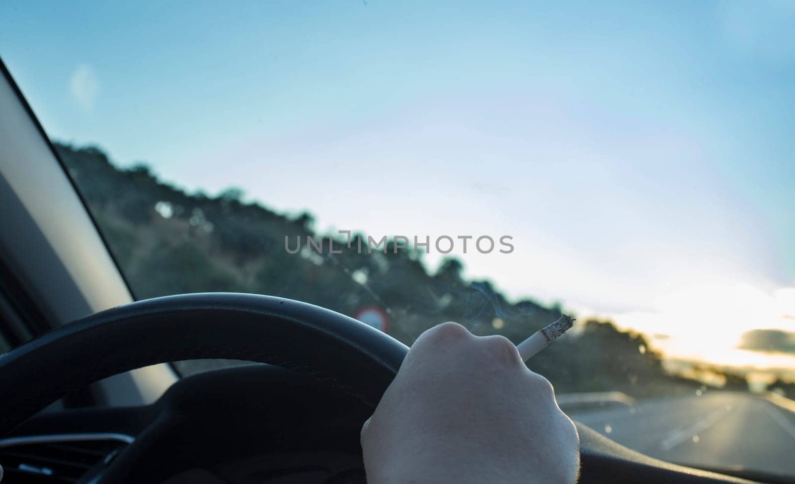 Woman smoking while she is driving. Cause of distracted driving accidents concept. Inside car view