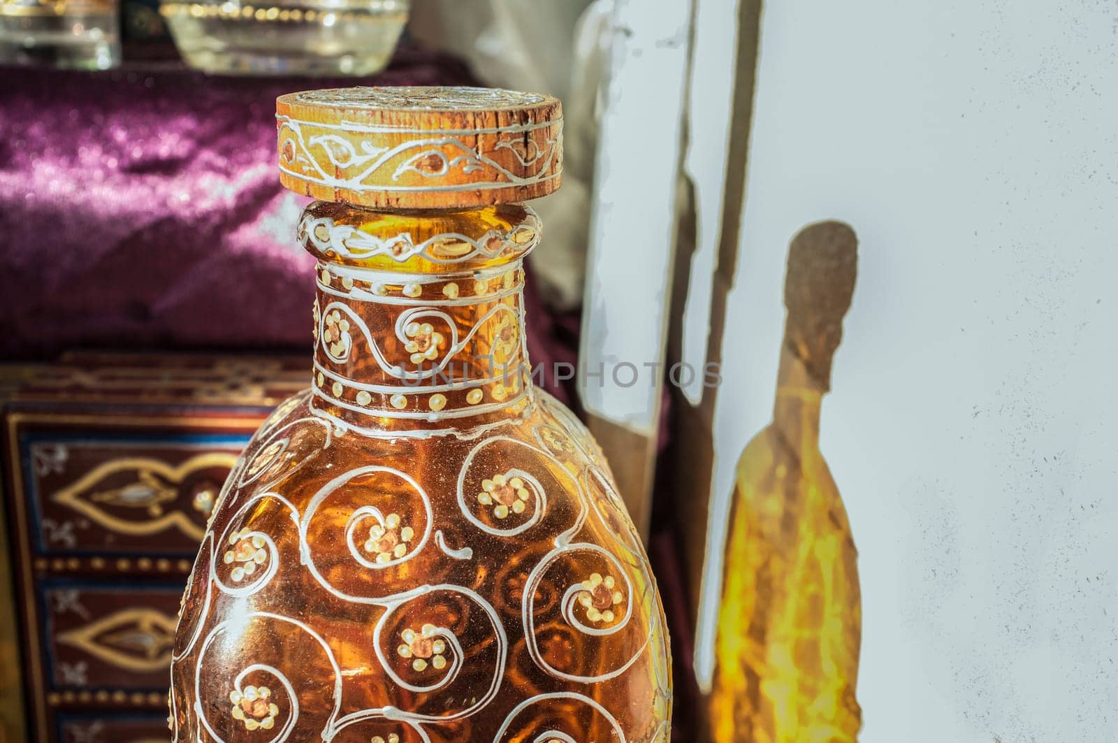Decorated glass bottle with floral motifs. Closeup, daylight
