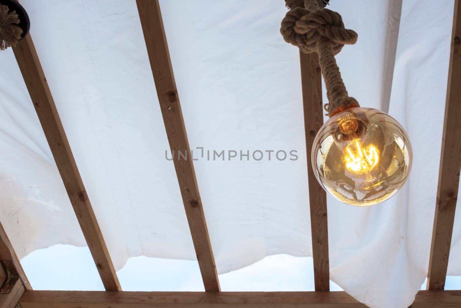 Rope light bulb over canvas pergola cover. Low angle view