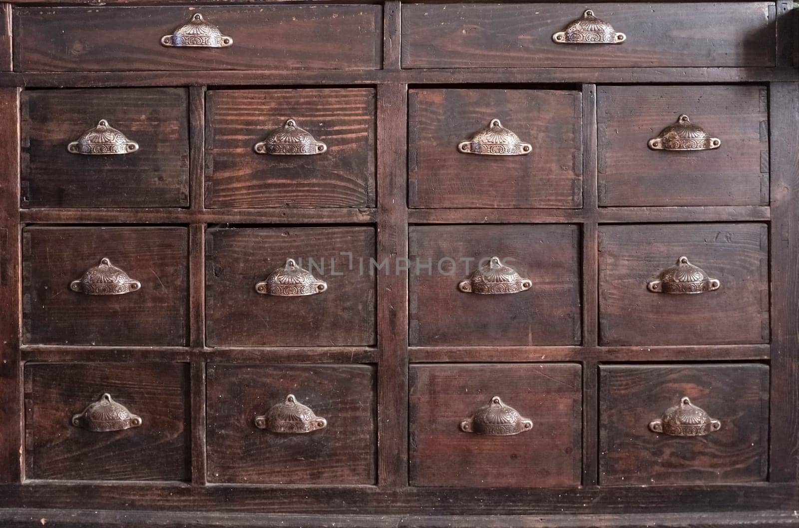 Dark brown wooden drawers furniture. Shell-shaped metal handles