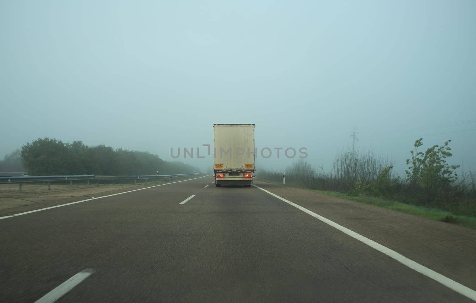 Driving behind a truck under dense fog. Bad-weather driving concept
