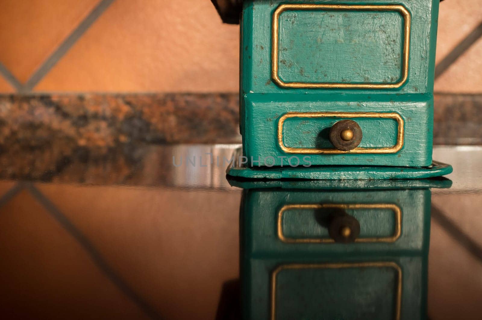 Old manual coffee grinder painted gold and green. Selective focus