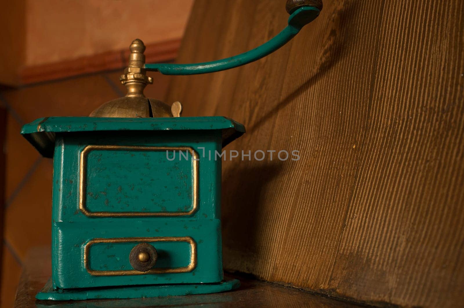 Old manual coffee grinder painted gold and green. Selective focus