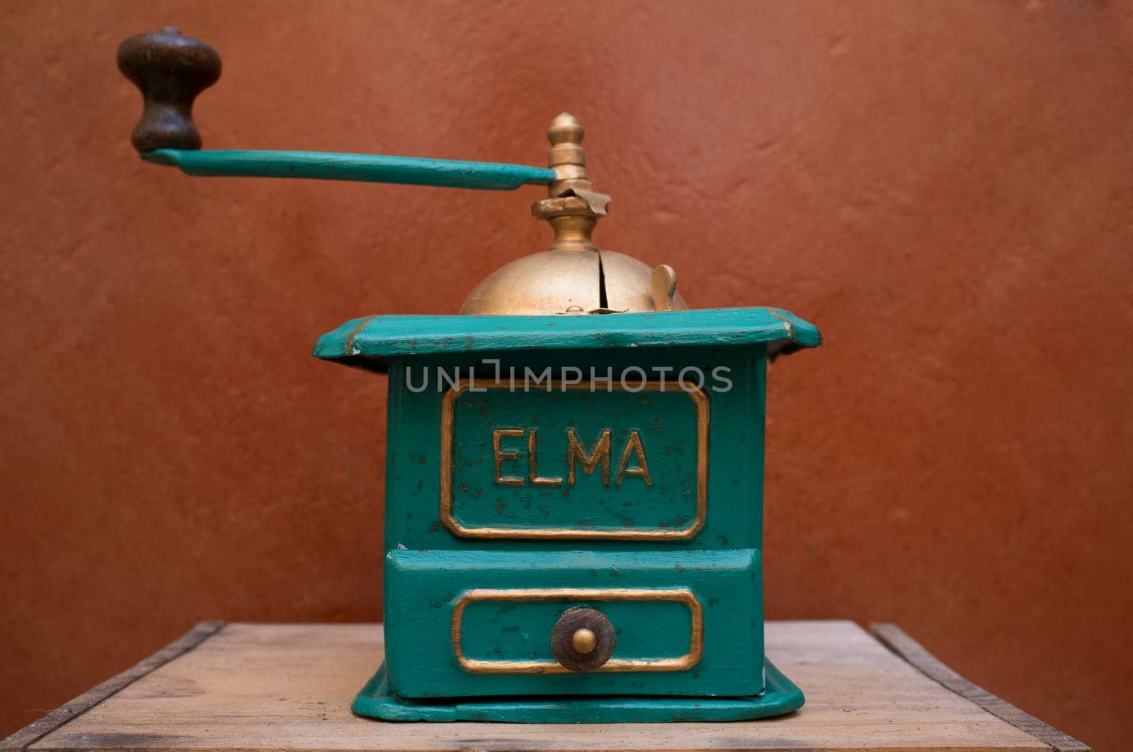 Old manual coffee grinder painted gold and green. Selective focus