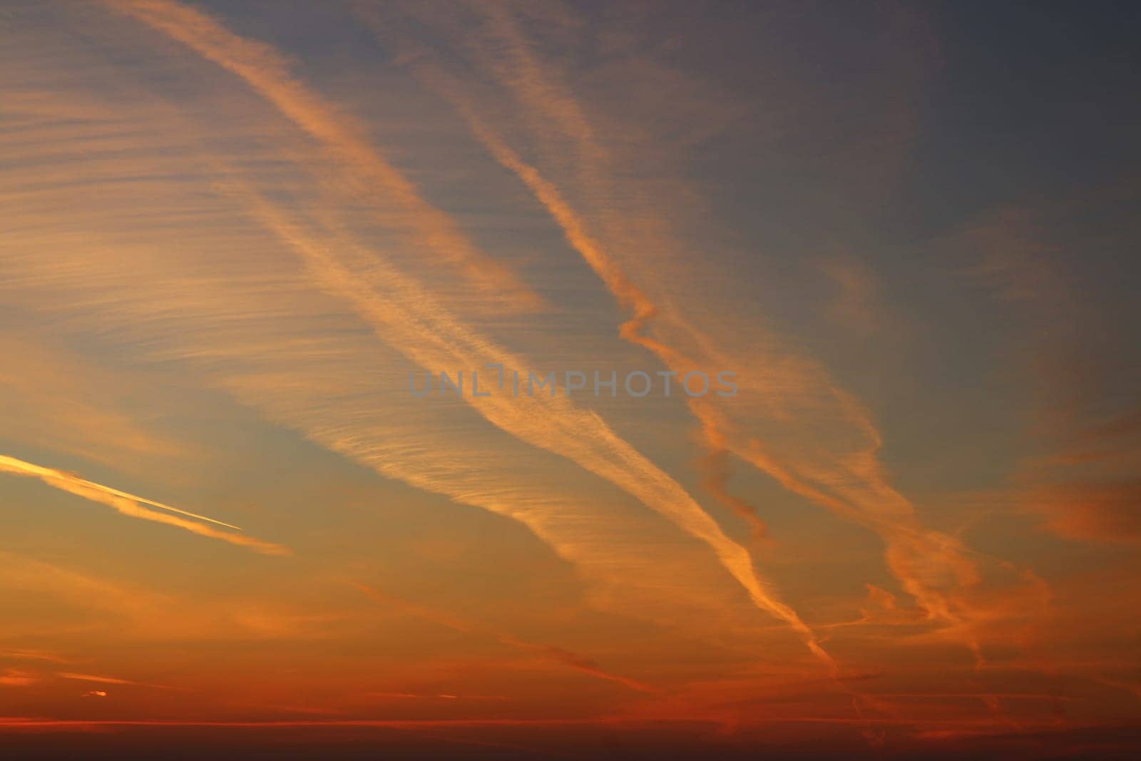 Red sky lit by the setting sun, aircraft trails