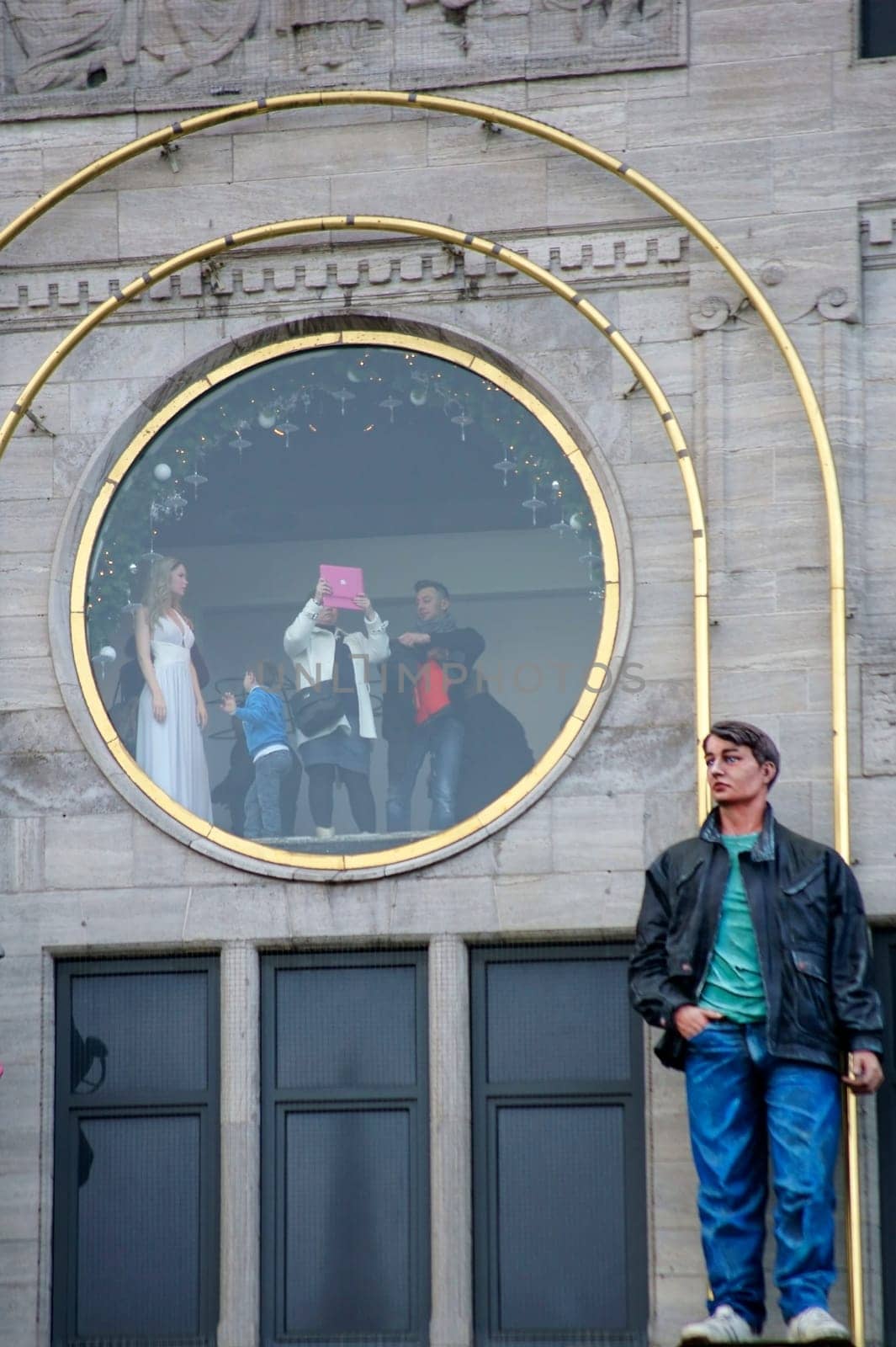 Amsterdam,Netherlands – December 29,2014: Tourists take pictures with a Tablet PC from a round viewing window of Madame Tussaud's Wax Museum on December 29,2014 in Amsterdam.