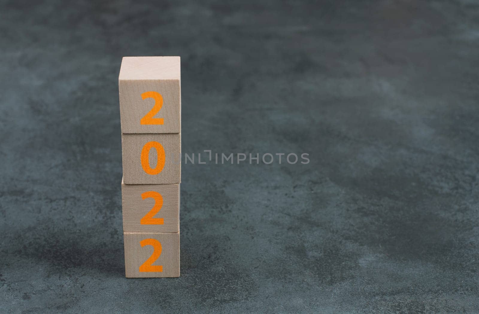 The year 2022 is standing on wooden cubes, dark background, empty copy space