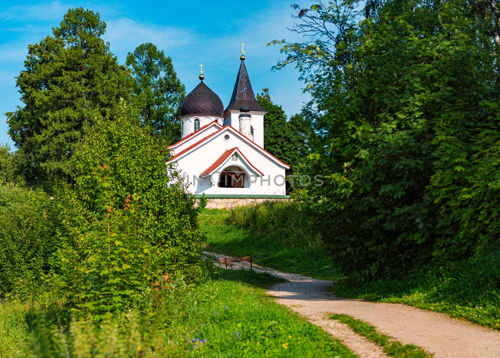 White russian church in summer with cloudy sky in background and road in foreground