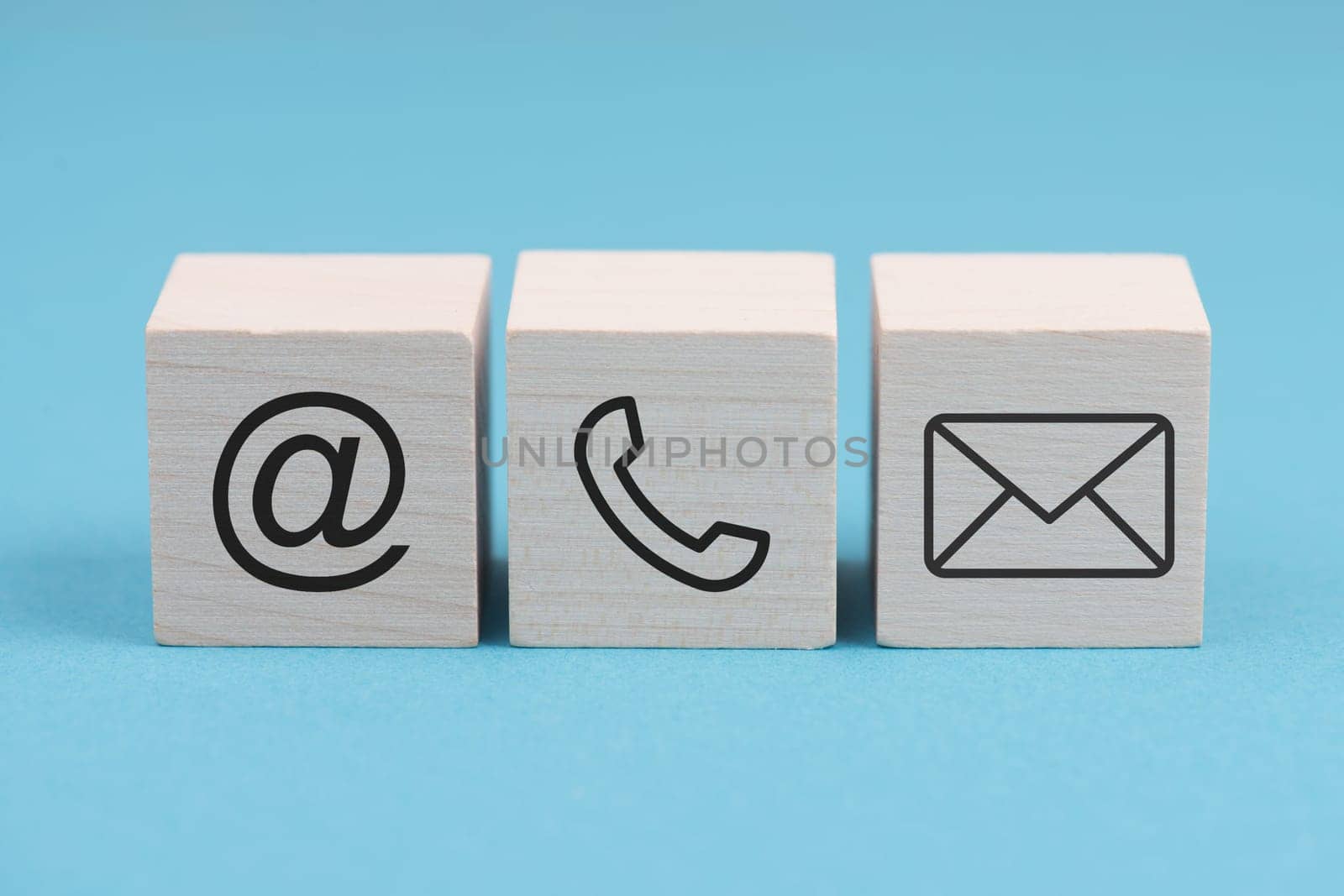 Signs for e-mail, phone and newsletter on wooden blocks, blue background, symbols and signs