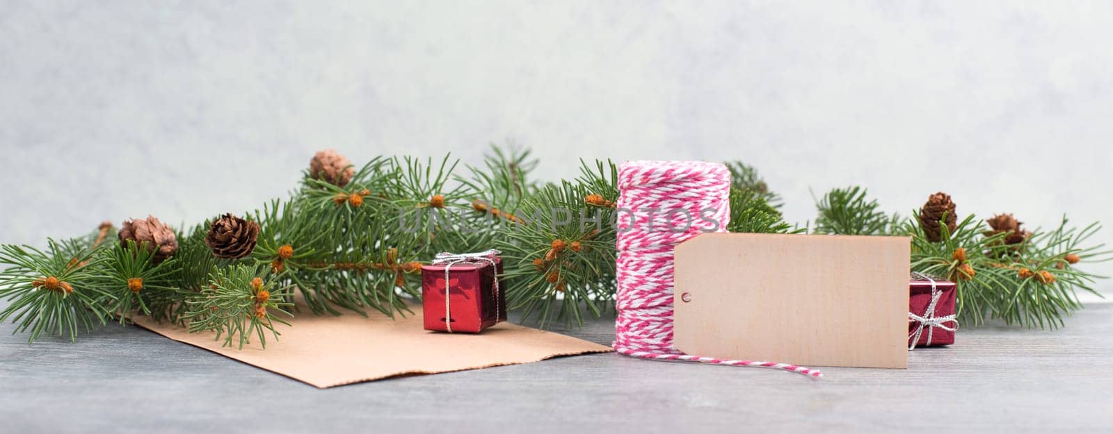 Christmas background with fir branch,little gift boxes,paper,ribbon and tag on a textured background, empty copy space