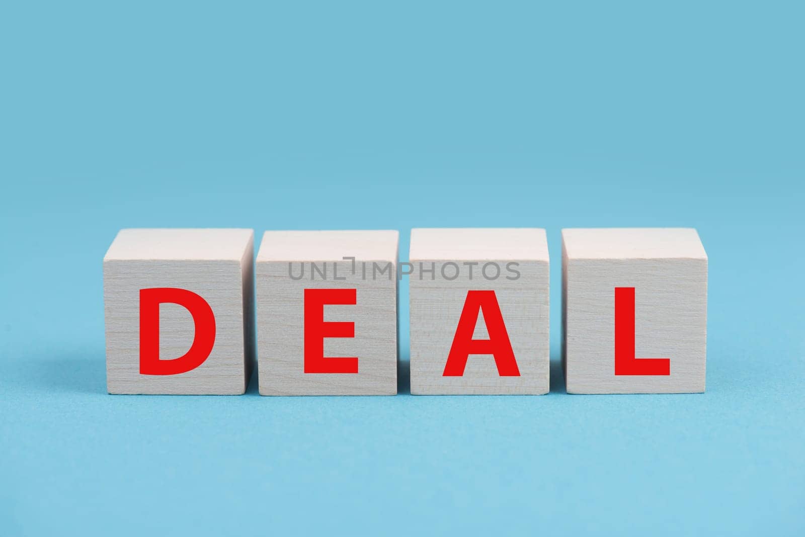 The word deal is standing in red letters on wooden cubes, blue background