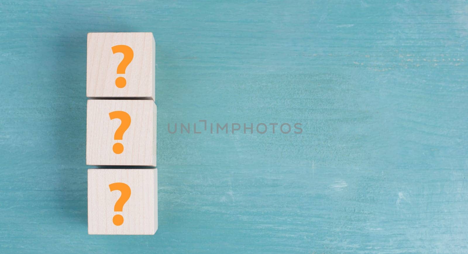 Three wooden cubes with question marks in orange color, empty copy space