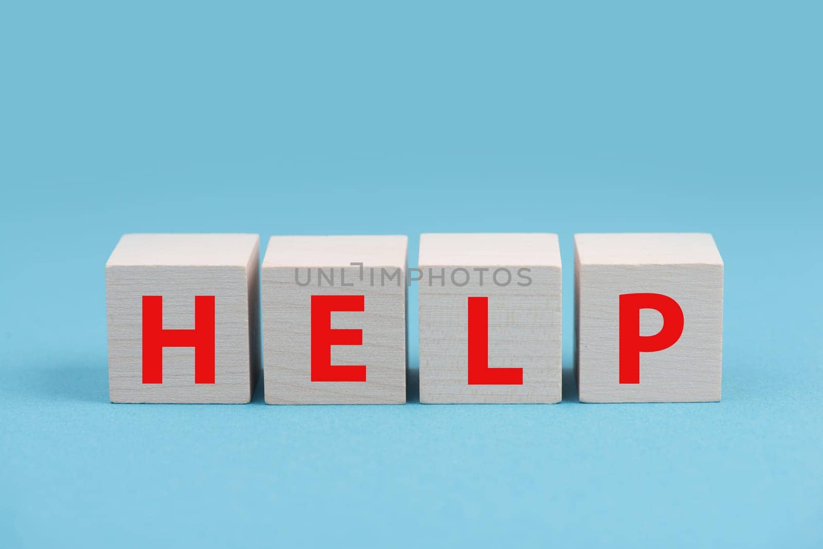 The word help is standing in red letters on wooden cubes, blue colored background