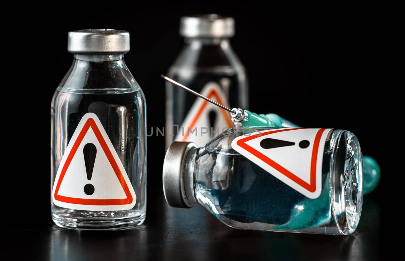 Vaccine bottles with red triangle exclamation mark sign on label, black background.