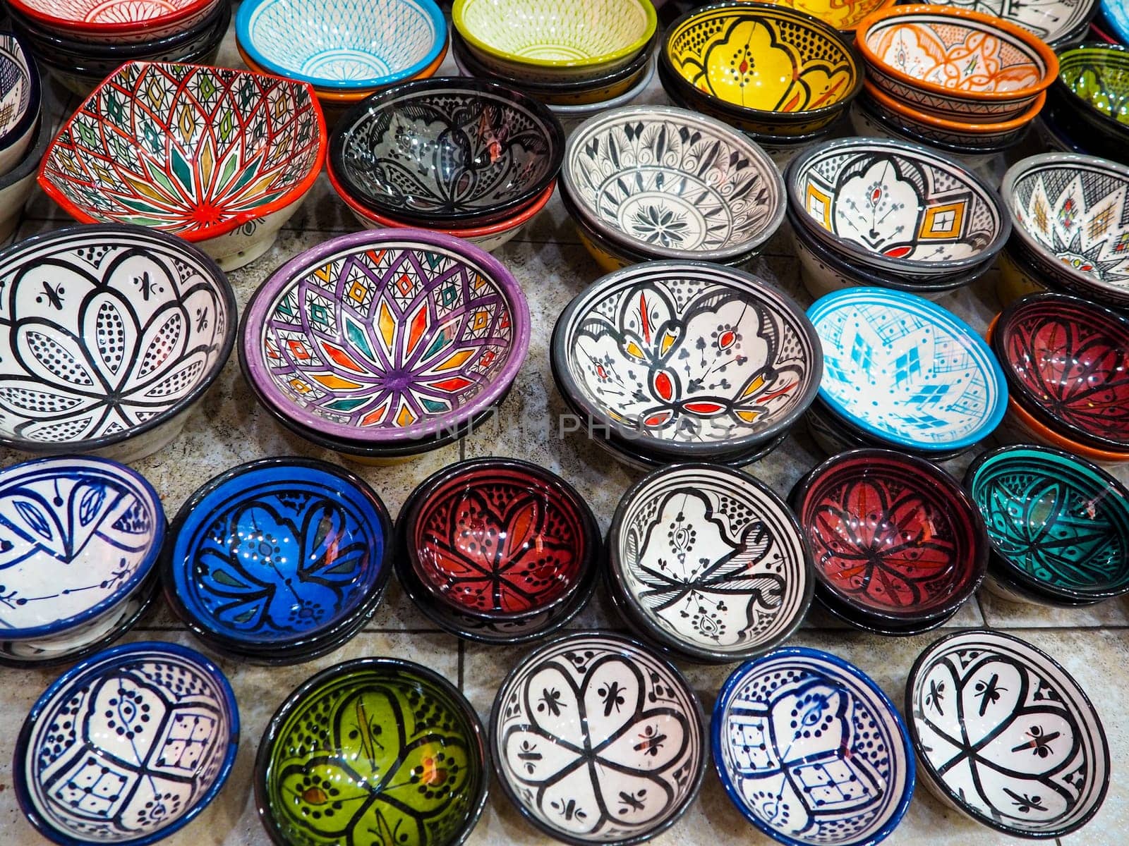 Handmade colourful decorated bowls or cups on display at traditional souk - street market in Morocco.