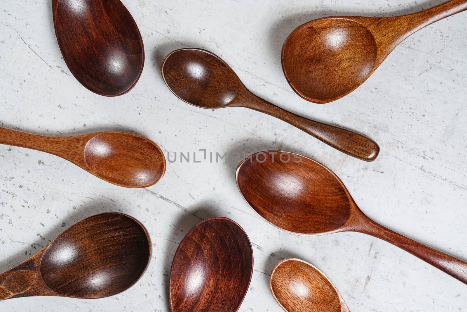 Small spoons made of dark wood, on white working board, view from above.