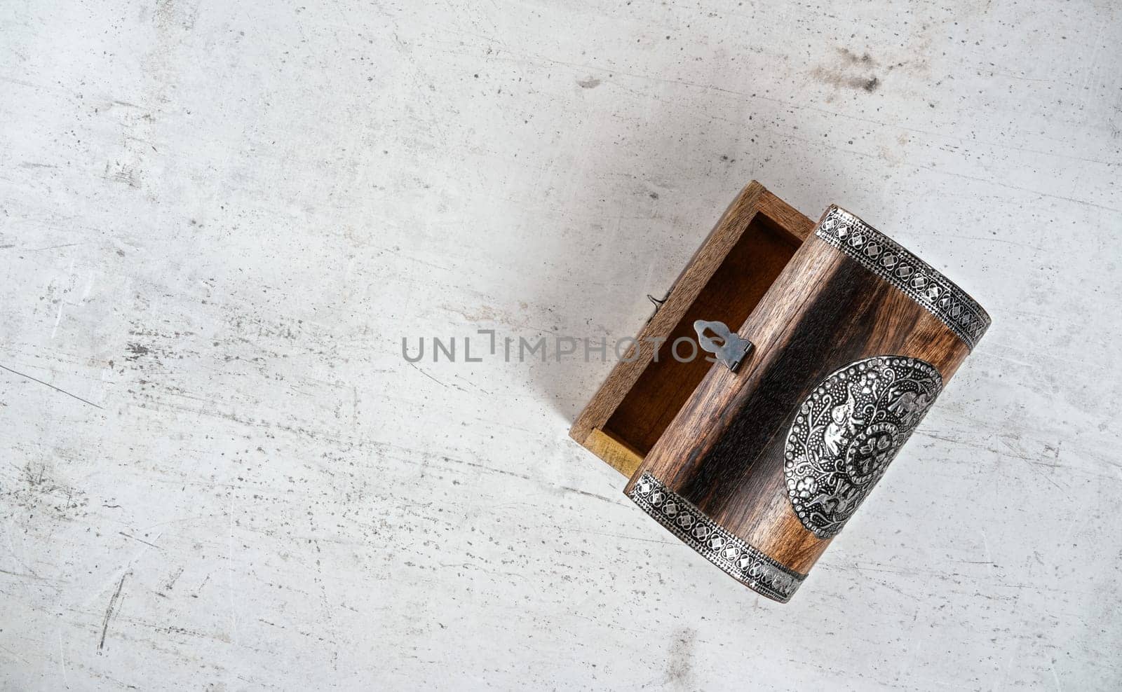 Small wooden decorated empty chest lid opened, on white stone board, photo from above.