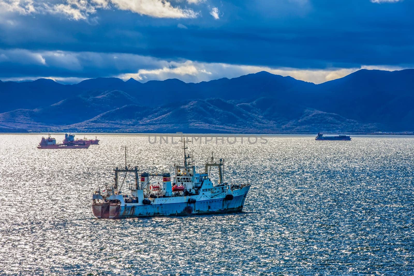 The large fishing vessel on the background of hills and volcanoes. Selective focus