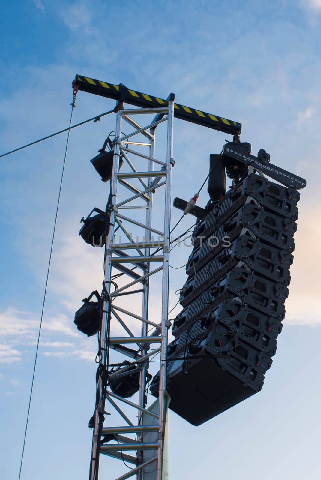 Line array speaker system hanging from pole during daylight performance. Sunset blue sky background