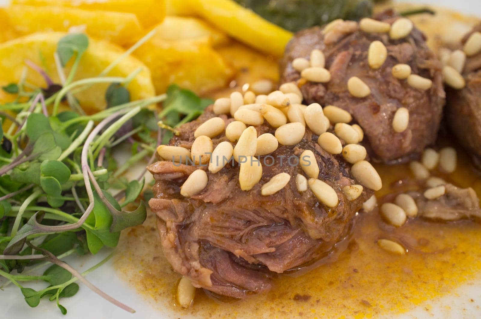 Stew cheek pieces of iberian topped with pine nuts and corn salad. Closeup
