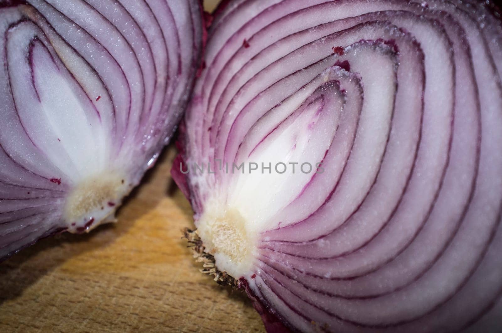 Cross sections of raw red onions. Closeup over wooden cutting board