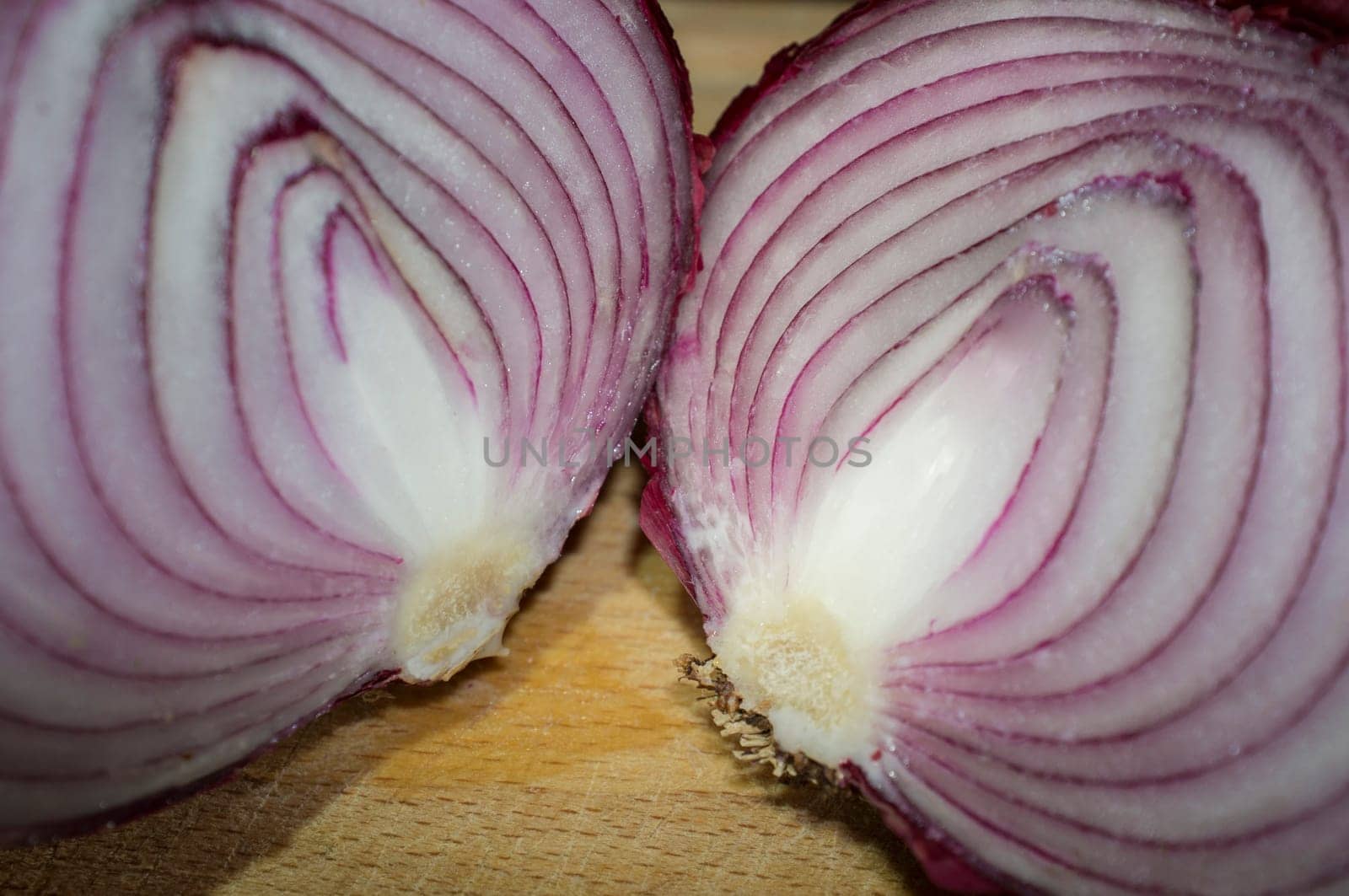 Cross sections of raw red onions. Closeup over wooden cutting board