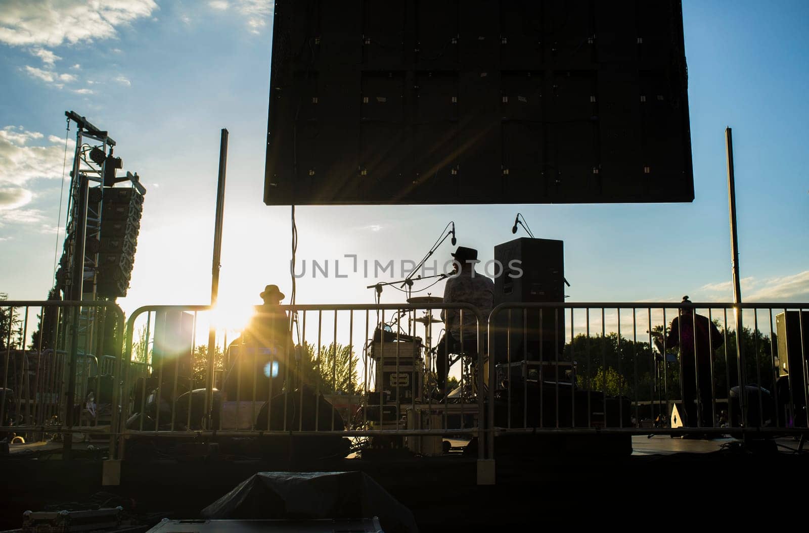 Rock daylight performance seen from rear stage. Sunset blue sky background