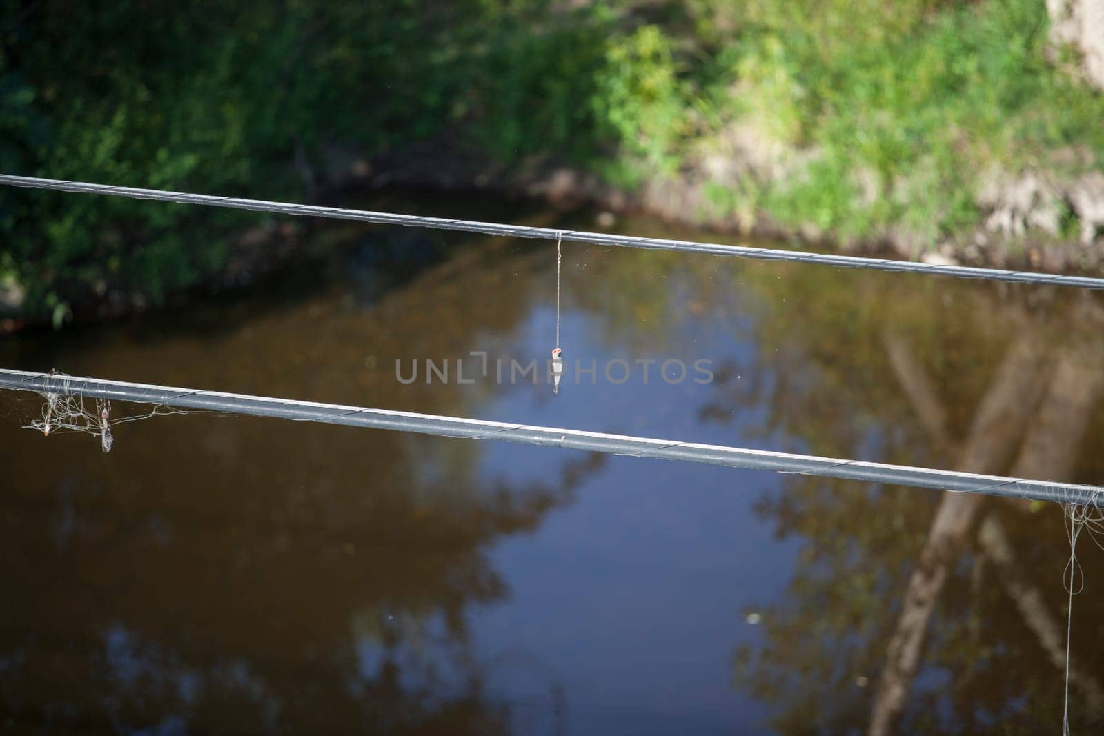 Some spoon lures tangled at electrical wire above the river. Selective focus