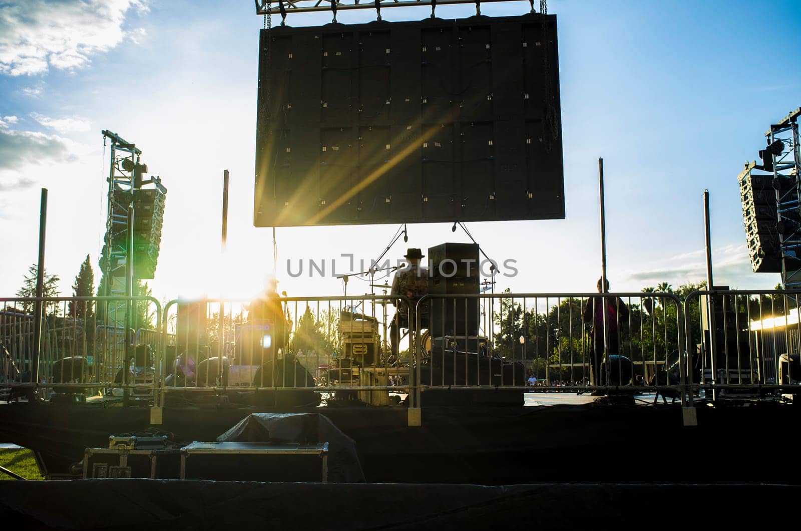 Rock daylight performance seen from rear stage. Sunset blue sky background