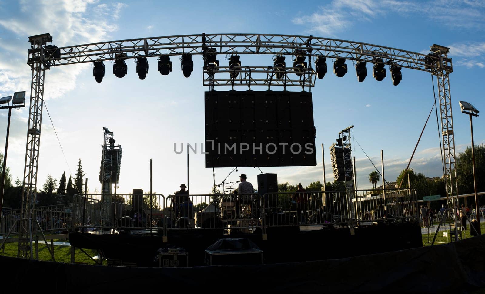 Rock daylight performance seen from rear stage. Sunset blue sky background