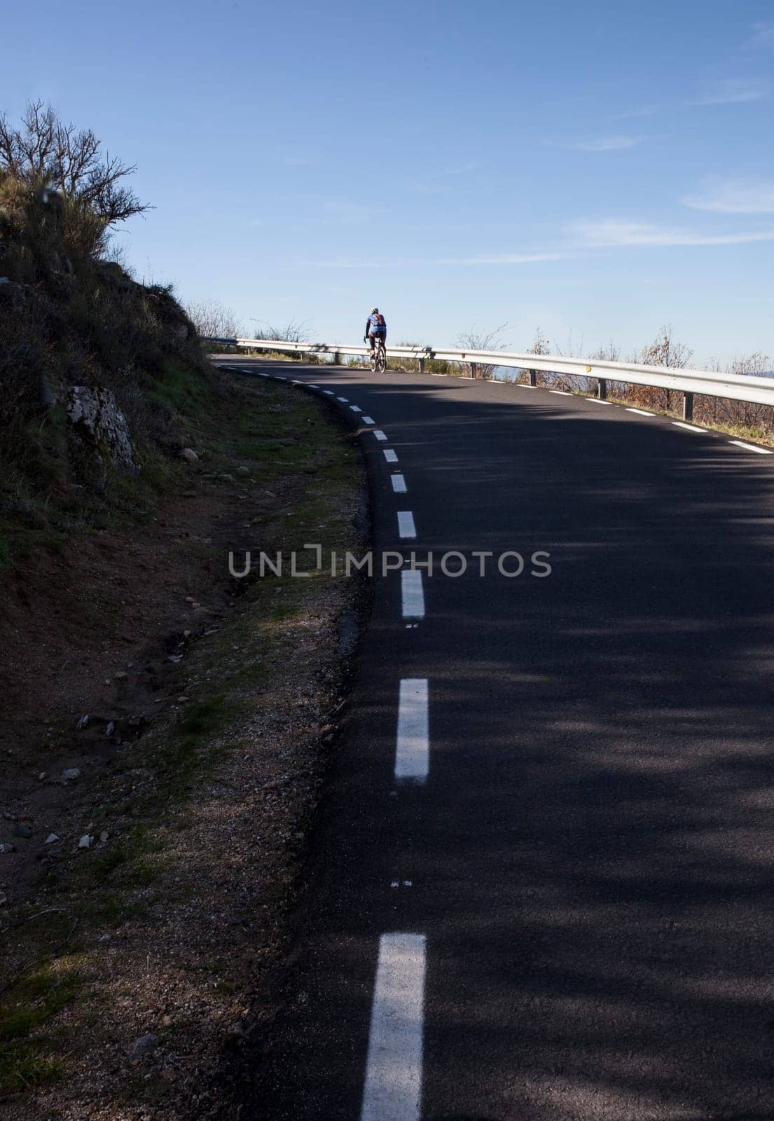 Mature biker ascending mountain pass. Road biking by Extremadura, Spain