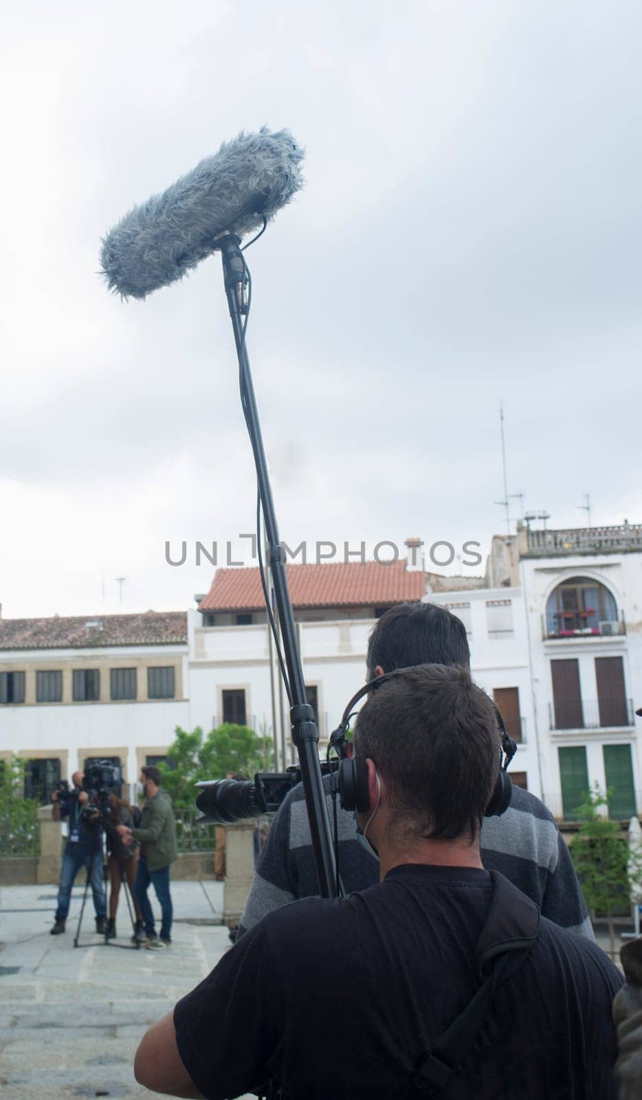 Sound technician with shotgun microphone covers a politician appearance. Local government press issues