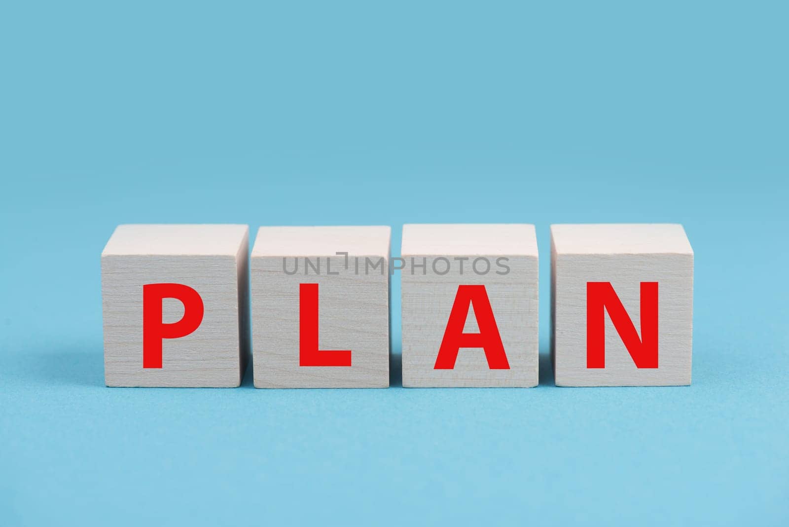 The word plan is standing on wooden cubes in red color, blue background
