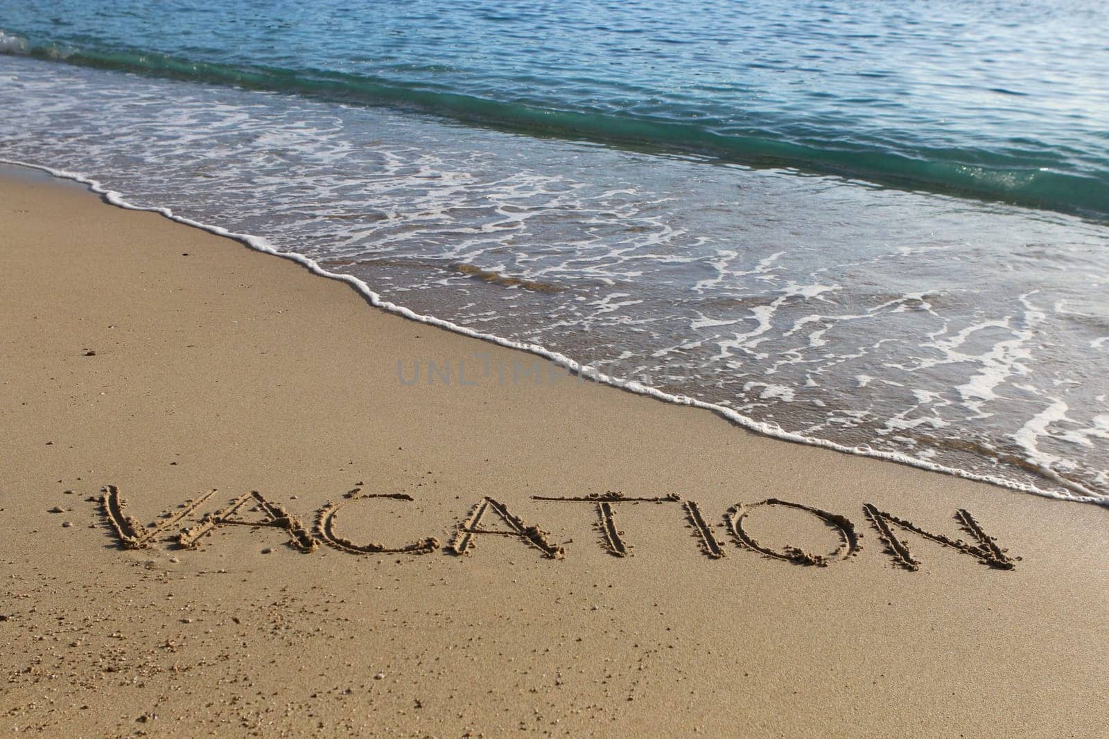 Vacation word written in the sand