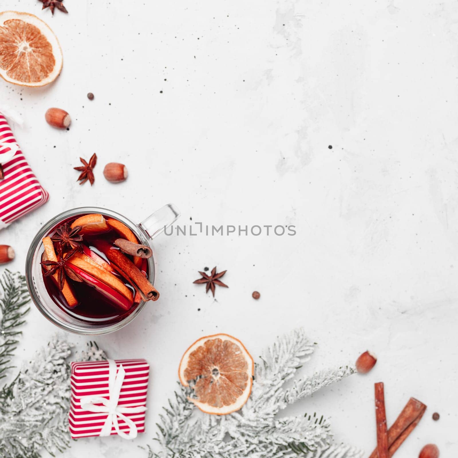 Christmas flat lay top view on gray concrete background with mulled wine glass cup or mug, red gift boxes, decorations, cinnamon sticks, hazelnut, orange, apple, various spices. Christmas time photo