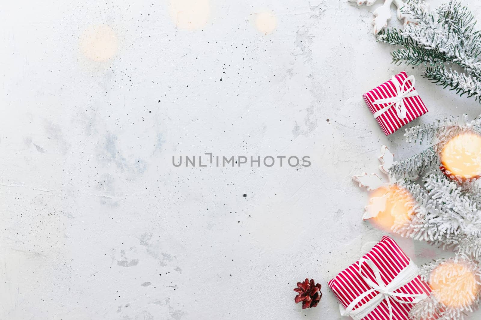 Christmas, New Year gray concrete flat lay. Red white striped present gift boxes top view. Gift ribbon and packaging paper. Christmas tree fir, cones, toy balls, wooden star. Copy space area on photo