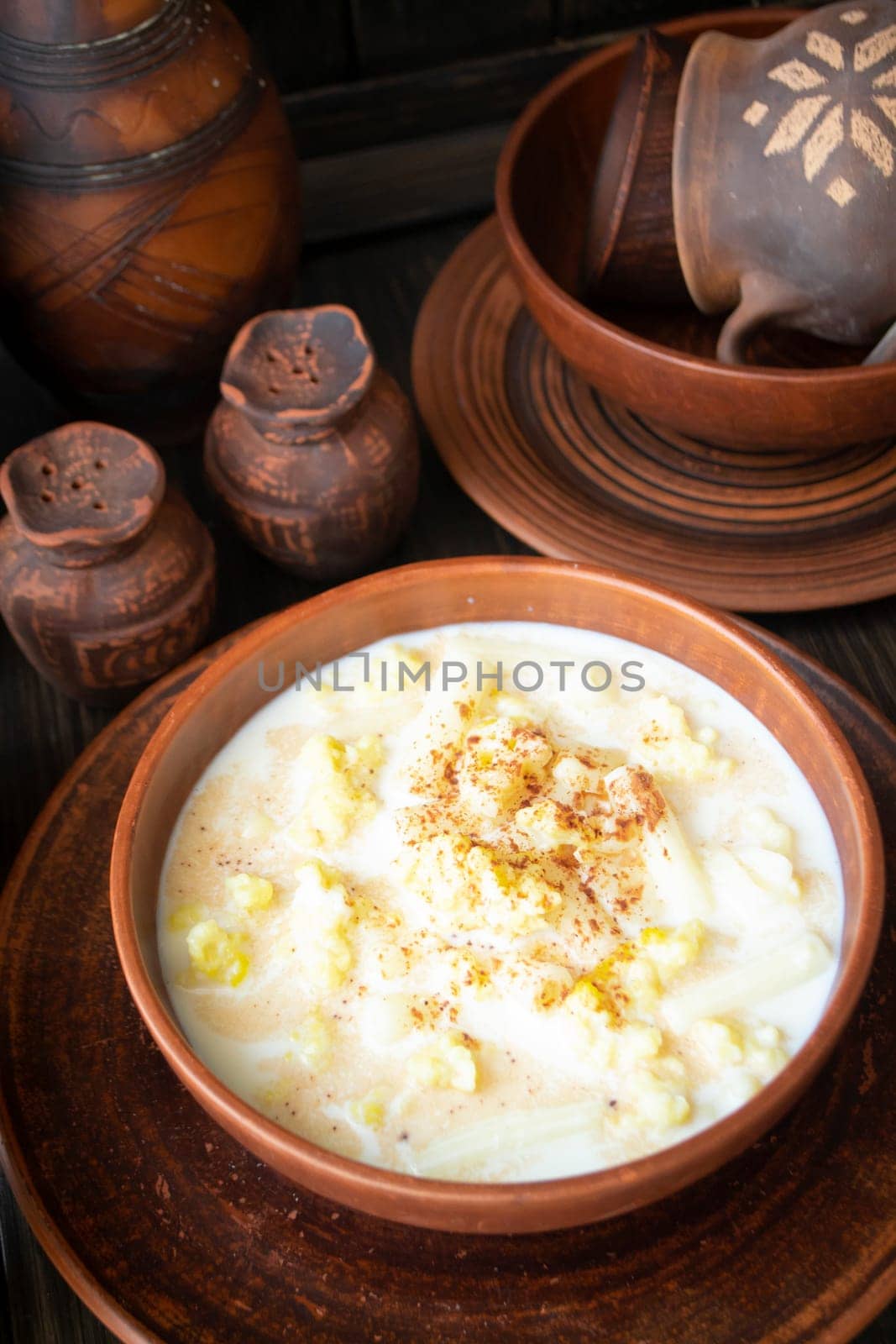 Milk soup on wooden table with pottery tableware, vertical image