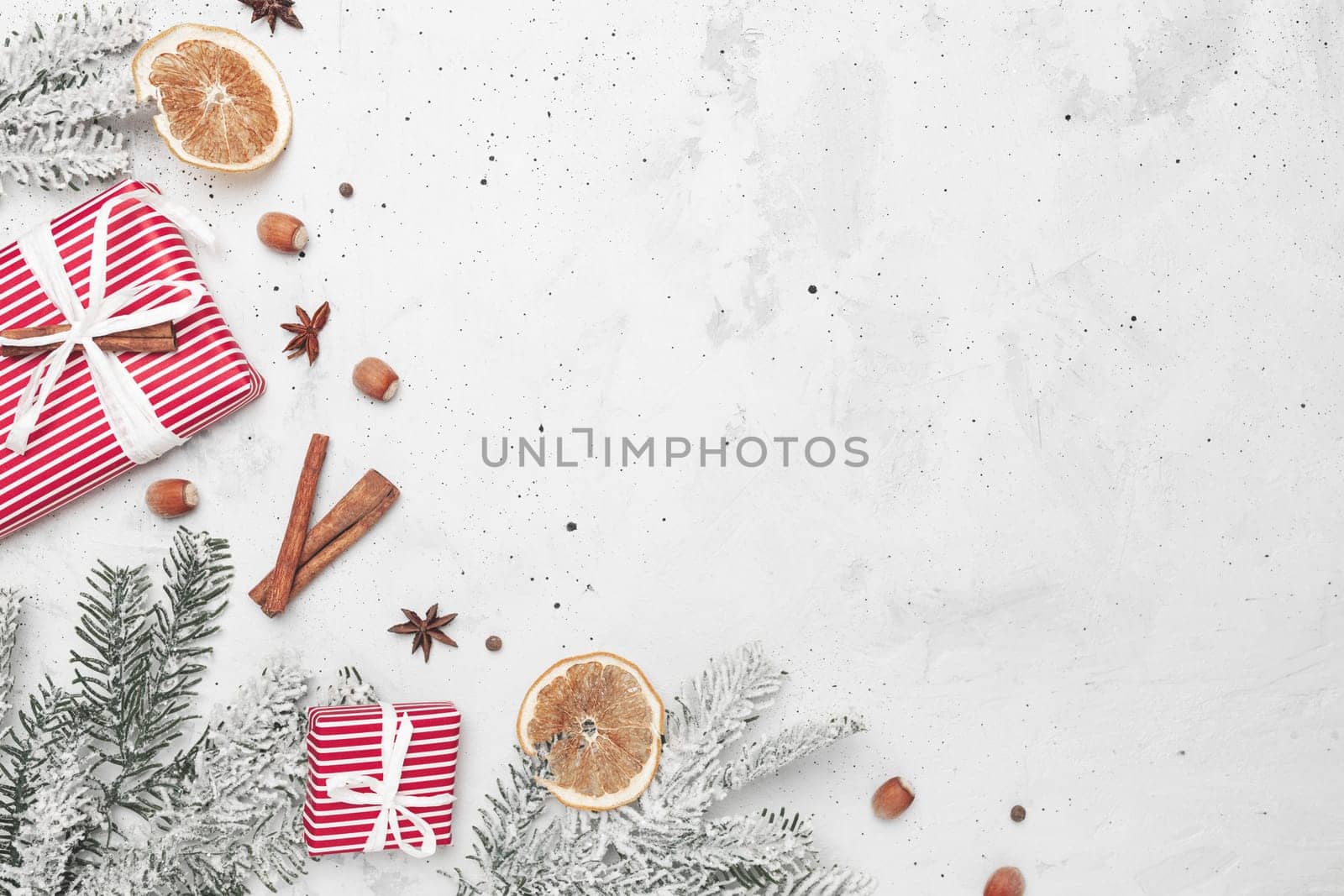Christmas flat lay top view on white gray concrete background table with present red gift boxes, decorations, cinnamon sticks, hazelnut, dried orange slices, various spices, fir, anise, aniseed