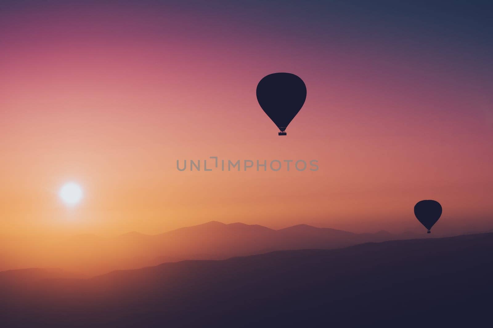landscape with hot air balloons black silhouette rising up to the sky at sunrise with beautiful high mountain panorama in the background