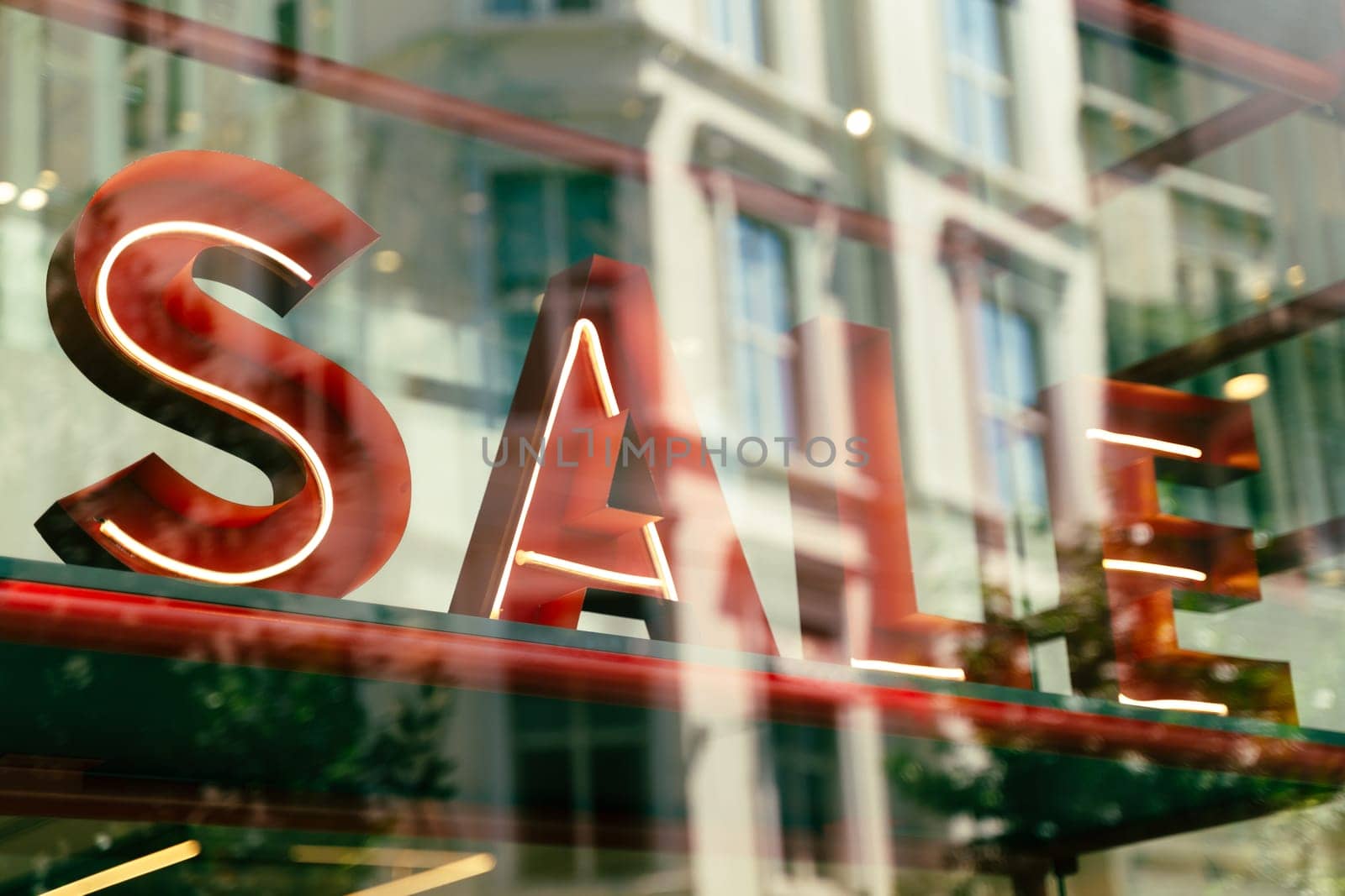 perspective closeup view of sale signage sign with volumetric neon letters in mall shop window with reflections on glass