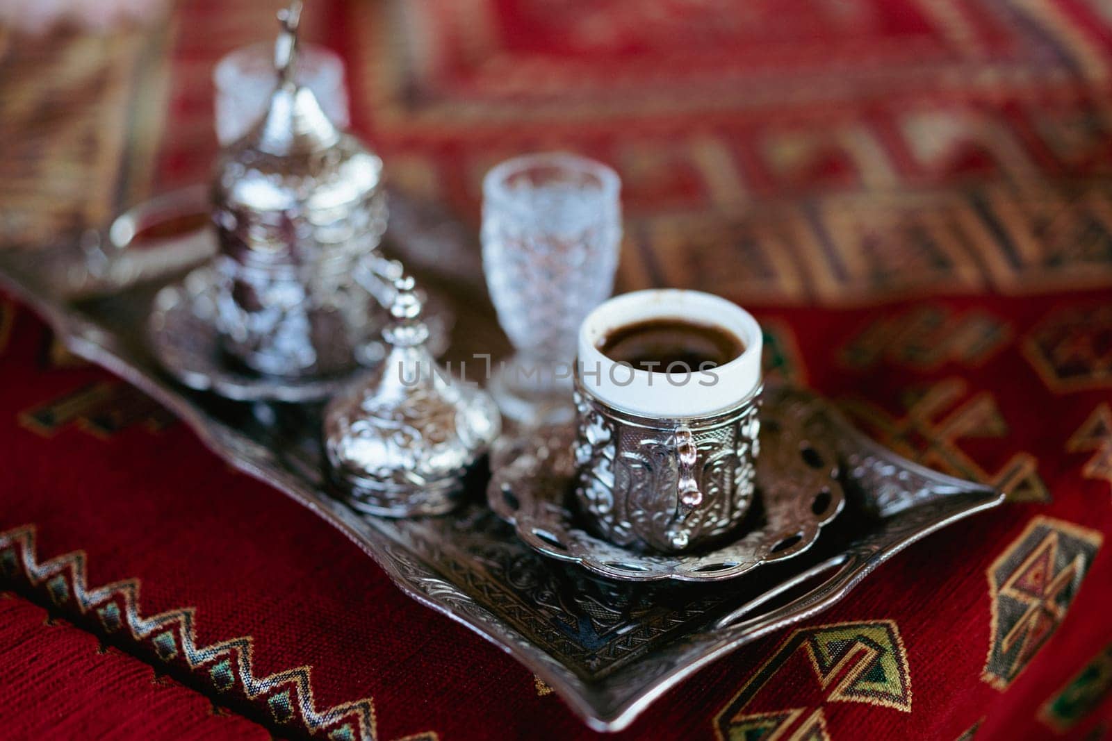 closeup of Turkish coffee served in traditional metallic cups and glass of water on silver tray at a restaurant